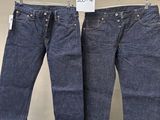 deux paires de jeans suspendues à un portant dans un magasin