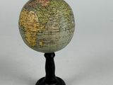 a small globe on a black stand on a white surface