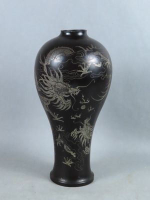 un vase noir orné d'un motif représentant un dragon