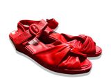 des sandales en cuir rouge posées sur une surface blanche, sur fond blanc