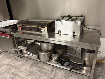 un plan de travail en acier inoxydable sur lequel sont posés des casseroles et des poêles