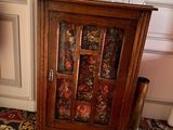 a wooden cabinet with a glass door in the corner of a room