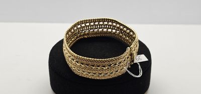 un gros plan d'un bracelet en or posé sur un chapeau noir
