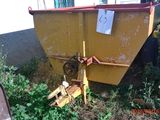 une benne jaune posée dans l'herbe à côté d'un immeuble