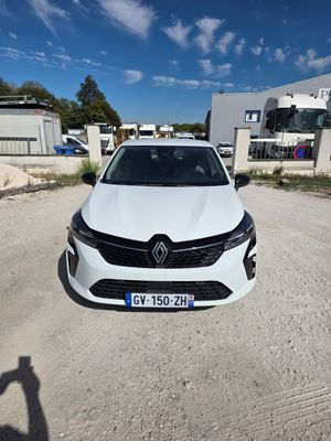 une voiture blanche garée sur un chemin de terre devant un bâtiment