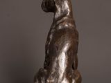 bronze statue of a dog sitting on a rock on a wooden table