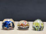 three glass vases sitting on a table with plants in them