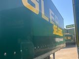 a green semi truck with a yellow and yellow sign on the side of it