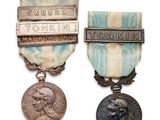 two medals are displayed on a white surface with a blue ribbon