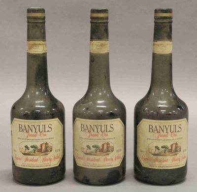 trois bouteilles de brandy sont alignées sur une surface blanche