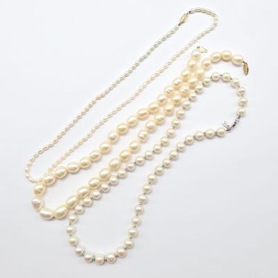 un collier de perles blanches composé de trois rangs de perles sur fond blanc