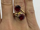 someone is holding a pair of rings with red stones on them