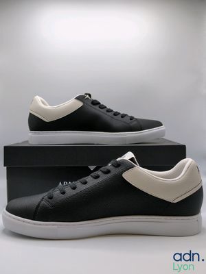 a pair of black and white sneakers sitting on top of a box