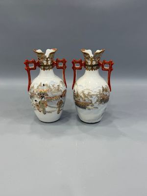 two white vases with red handles on a gray surface