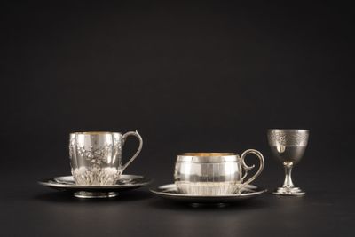 deux tasses et soucoupes argentées posées sur un fond noir