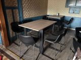 tables and chairs in a room with a wallpapered wall behind them