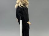 doll with blonde hair standing on a white pedestal on a gray background