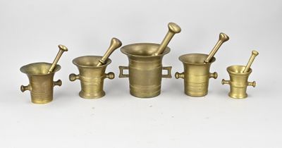 un ensemble de mortiers et de pilons en laiton posés sur une surface blanche