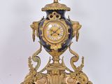 a clock that is sitting on a stand on a white surface