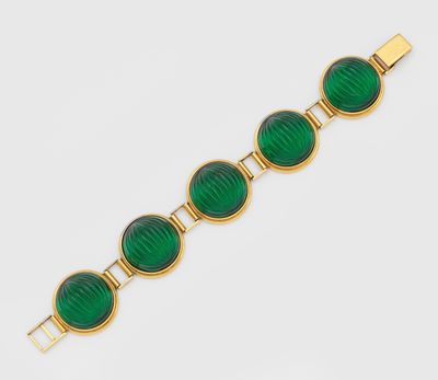 un bracelet en or orné de perles de verre vertes sur fond blanc