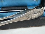 a silver spoon and spoon rest in a black case