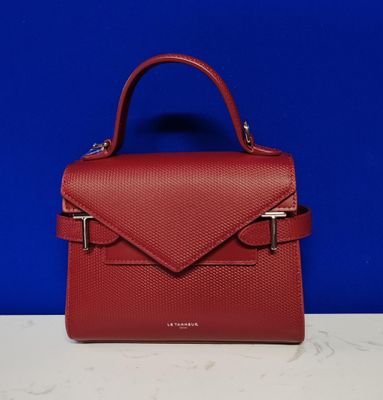 un sac à main rouge posé sur un comptoir, près d'un mur bleu