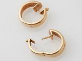 two pairs of gold hoop earrings on a white surface