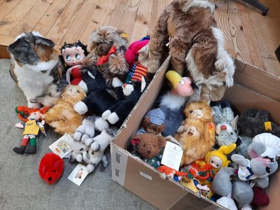 beaucoup de peluches dans une boîte posée par terre