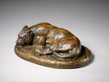 bronze statue of a dog resting on a rock