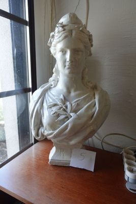 une statue représentant une femme assise sur une table près d'une fenêtre