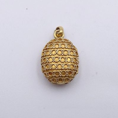 gros plan d'un pendentif plaqué or sur une surface blanche