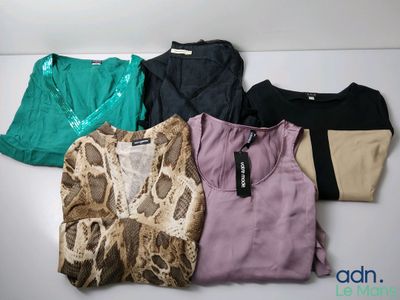 Plusieurs chemises de différentes couleurs sont alignées sur une surface blanche.