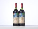 two bottles of red wine sitting on top of a table
