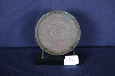 une vieille plaque en bronze posée sur un socle noir, avec une étiquette blanche