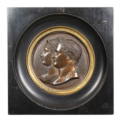 bronze medallion of a man and a woman in profile on a black background