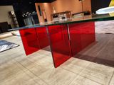 a glass table with a red table top on a tile floor