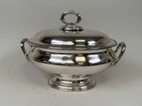 a silver plate with a lid and handles on a white surface