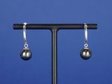 une paire de boucles d'oreilles en forme de boules argentées posées sur un socle noir