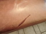 a brown leather couch with a stain on it