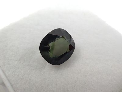 a green tourmaline gemstone on a white cushion