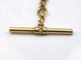 a close up of a gold cross on a chain on a white surface
