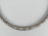 a close up of a necklace on a white surface with a pair of scissors