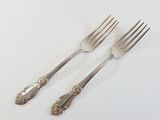 two forks and two spoons sitting on a white surface