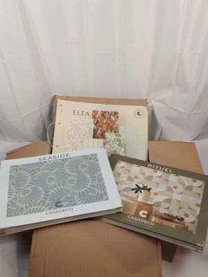 several books are stacked on top of a cardboard box on a bed