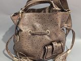 sac à main en cuir avec des pompons et des anses en cuir, sur fond blanc