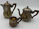 deux théières en argent et une cafetière en argent posées sur un plan de travail blanc
