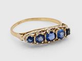 gros plan d'une bague en or avec des saphirs bleus