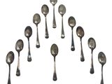 six silver spoons are arranged in a circle on a white surface