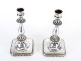 pair of silver candlesticks on a white surface with a white background