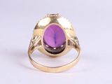 a close up of a gold ring with a purple stone in it